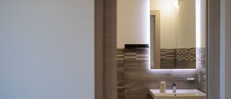 A bathroom with a sink, mirror, and tiled walls.