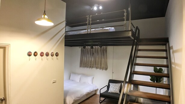 Una habitación pequeña con literas, un escritorio, una silla y una escalera.