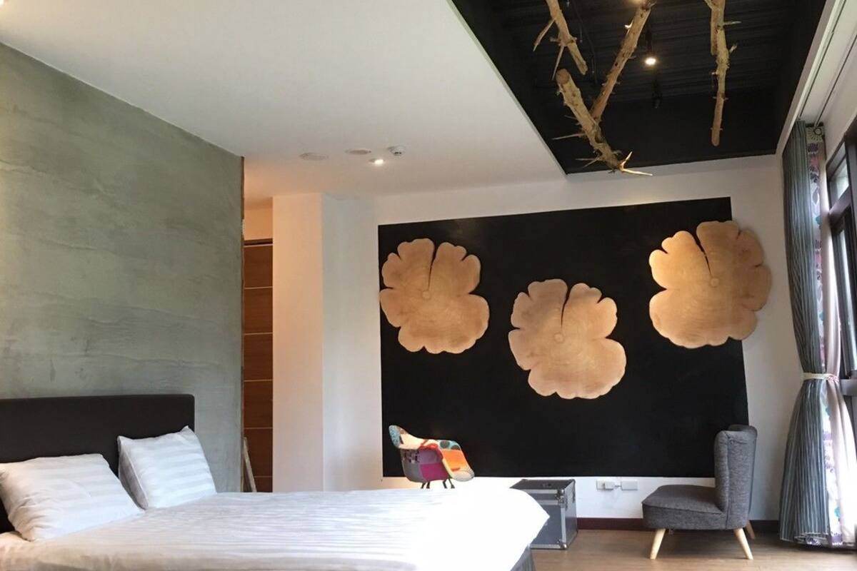 Un dormitorio moderno con dos camas, una gran obra de arte en la pared y un diseño de techo único.