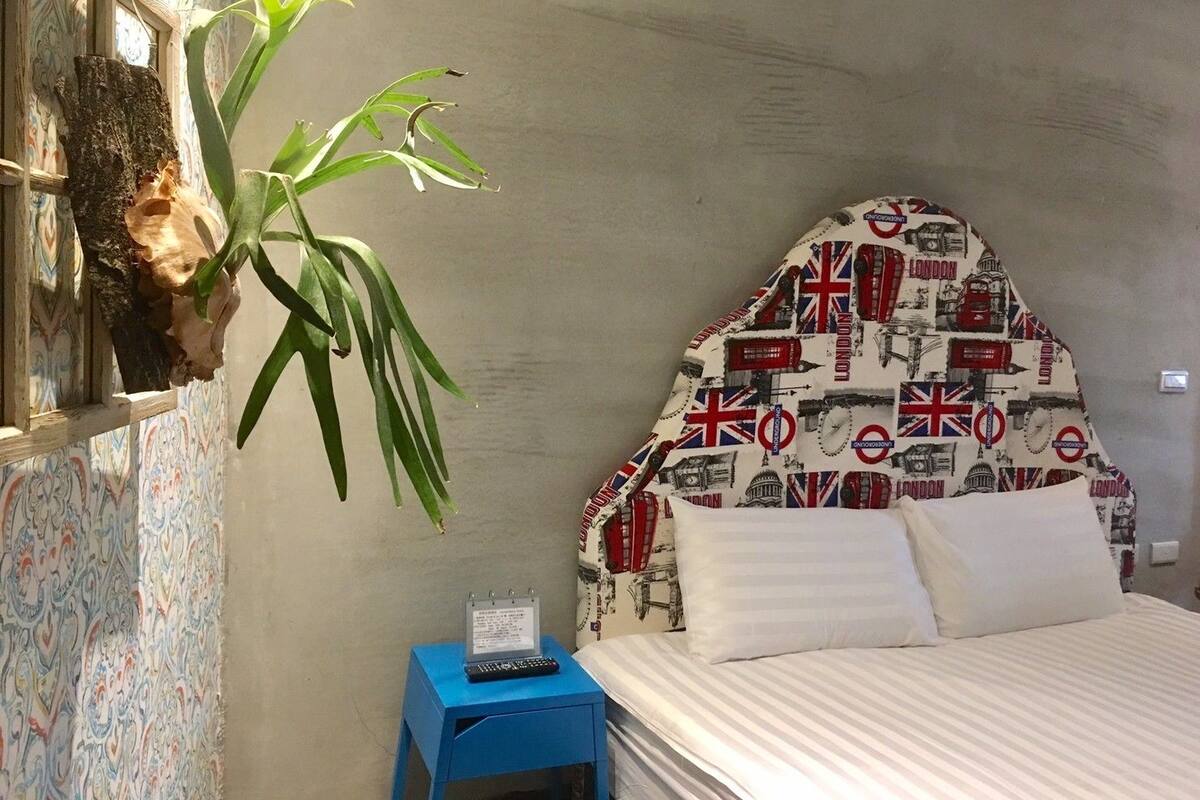 Un dormitorio con una cama, una mesita de noche azul, un calendario y una pared con papel tapiz estampado.