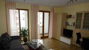 A living room with a sofa, a coffee table, a TV, and a dining area. - Abendsonne (Bamberg)