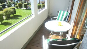 A balcony with a small round table and two chairs, one with a green and white striped cushion. - Abendsonne (Bamberg)