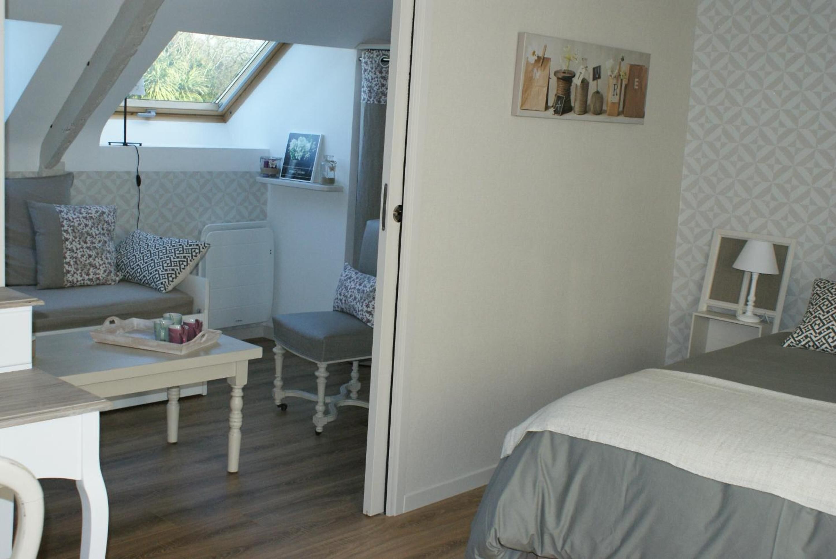 A bedroom with a skylight, a bed, a desk, and a chair.