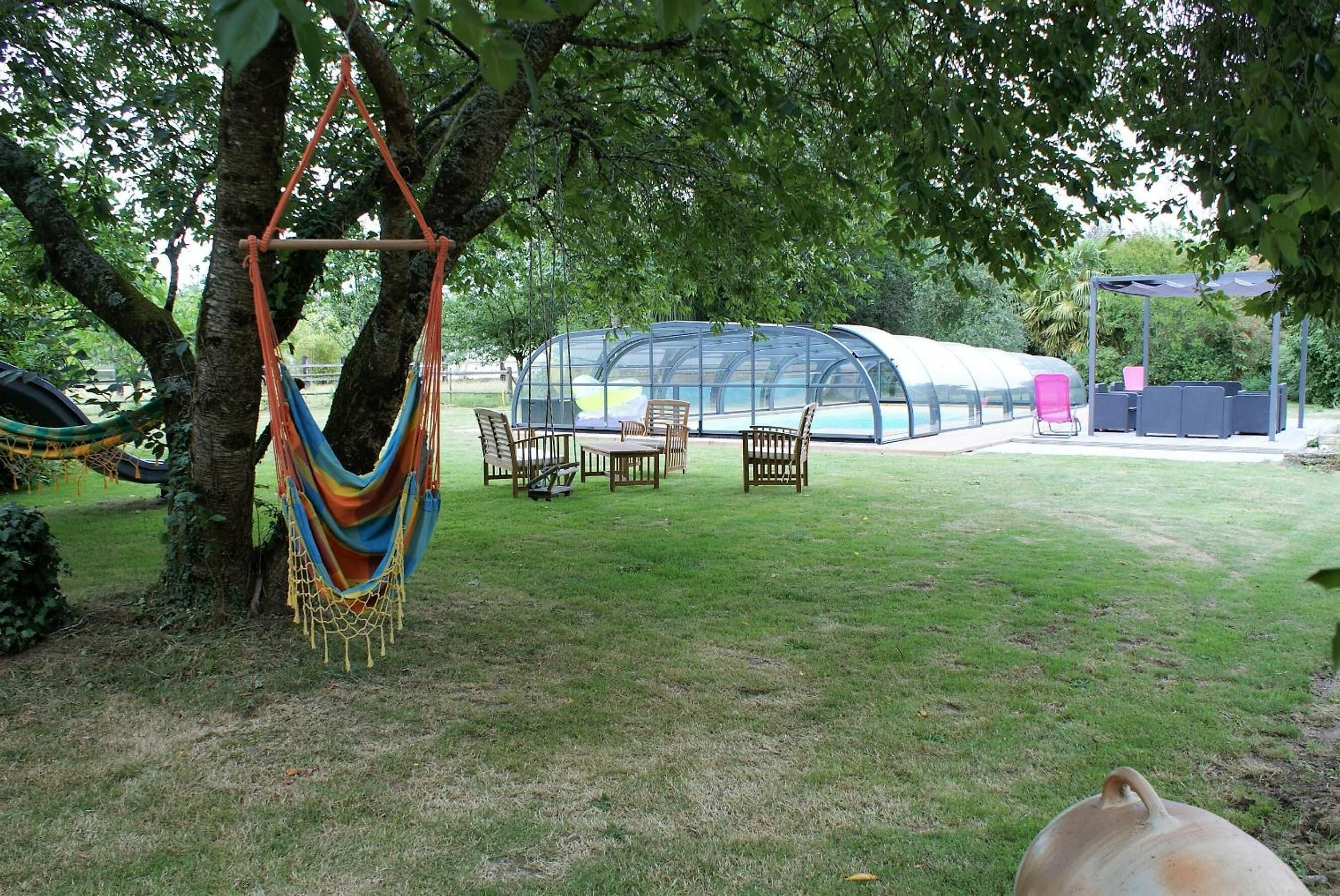 Un espace extérieur abrité, avec des chaises et un hamac sous un arbre.