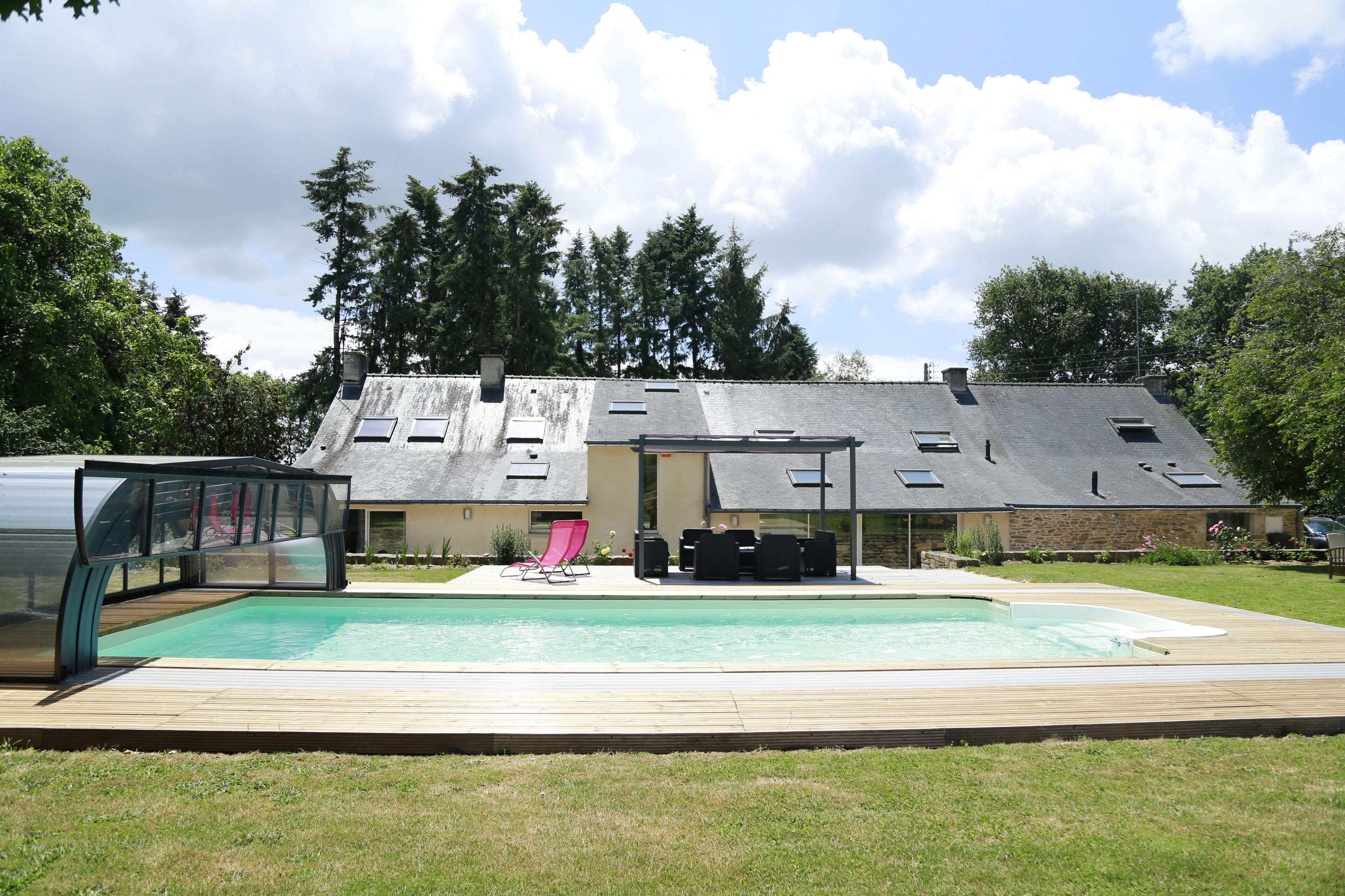 Ein Haus mit Swimmingpool, überdachter Terrasse und einer Holzterrasse.