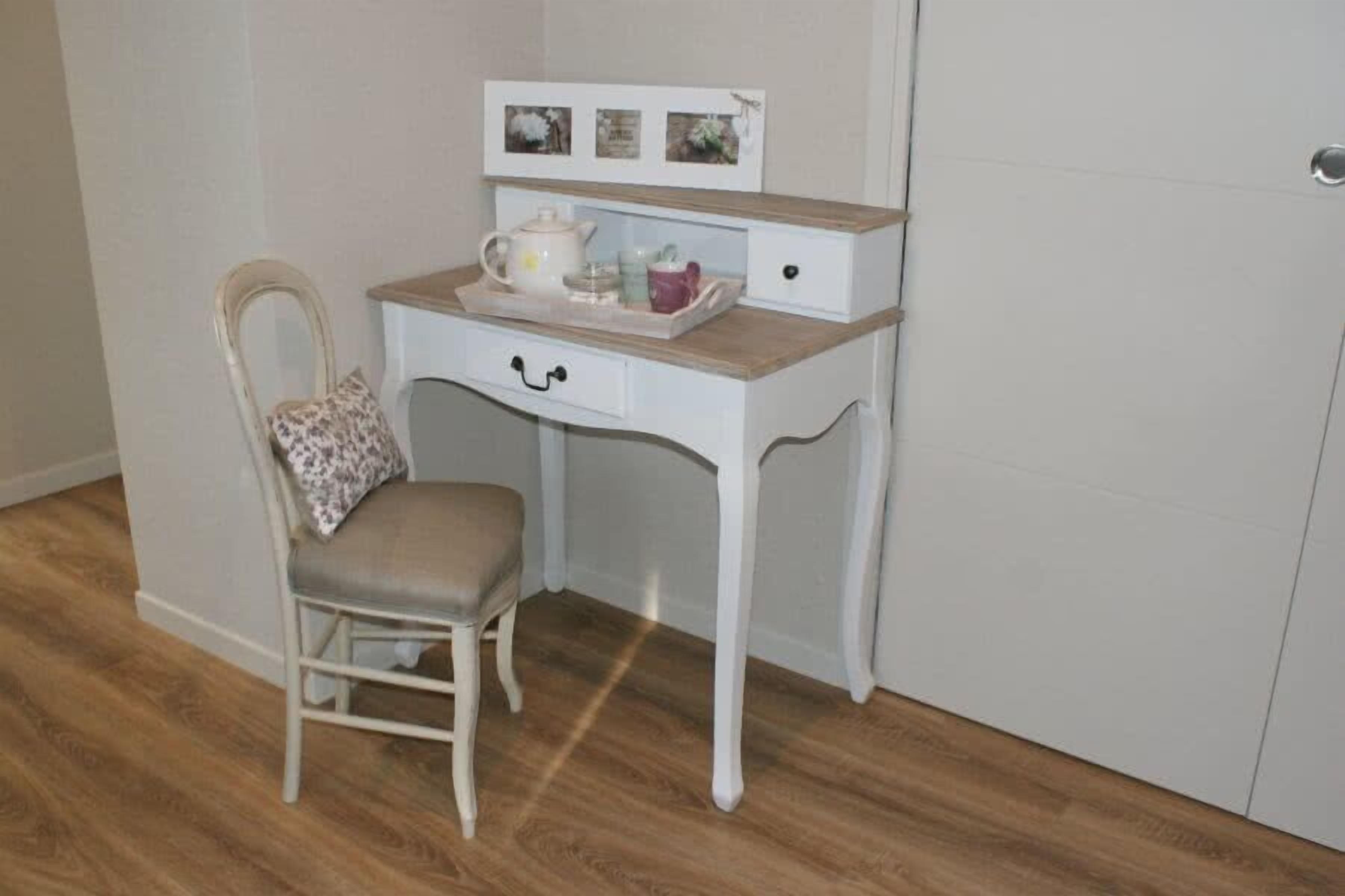 A small white desk with a chair, a tray with a teapot, cups, and a picture frame on the wall above.