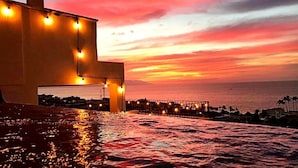 Une vue sur le coucher de soleil depuis un hôtel situé au bord de l’eau, avec une jetée qui s’avance dans l’eau.