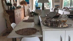 Una cocina moderna con una isla central, armarios de madera y una zona de comedor con sillas blancas.