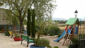 A children's play area with a slide, benches, and potted plants.