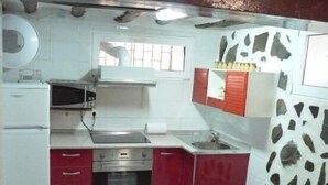 A compact kitchen with white cabinets, a red countertop, a microwave, a stove, and a sink.