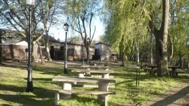 A park with picnic tables, lamp posts, and trees.