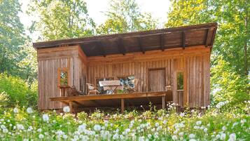 Ein rustikales Holzhaus mit Veranda, umgeben von einem Feld weißer Blumen.