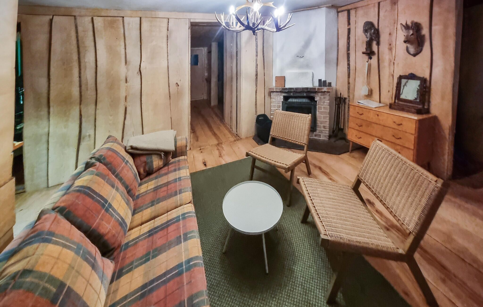 Ein gemütlicher Raum mit einer Couch, einem kleinen runden Tisch, Korbstühlen, einem Kamin und einer Chandelier.