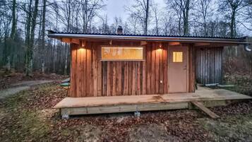 Eine kleine Holzhütte mit einem Fenster und einer Tür, umgeben von einem Wald.