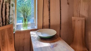 A wooden interior with a window, a vase with branches, and a bowl on a table.