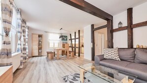 A modern living room with a glass coffee table, a grey sofa, and a patterned rug. - Apartments am Markt (Bernkastel-Kues)