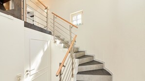 A staircase with a wooden handrail and metal balusters, leading to a landing with a small window. - Apartments am Markt (Bernkastel-Kues)