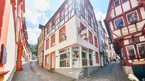 A narrow cobblestone street lined with traditional half-timbered buildings, one with a visible shop sign. - Apartments am Markt (Bernkastel-Kues)