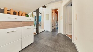 A modern hallway with a white wardrobe, a wooden accent, and a 'Home' sign. - Apartments am Markt (Bernkastel-Kues)