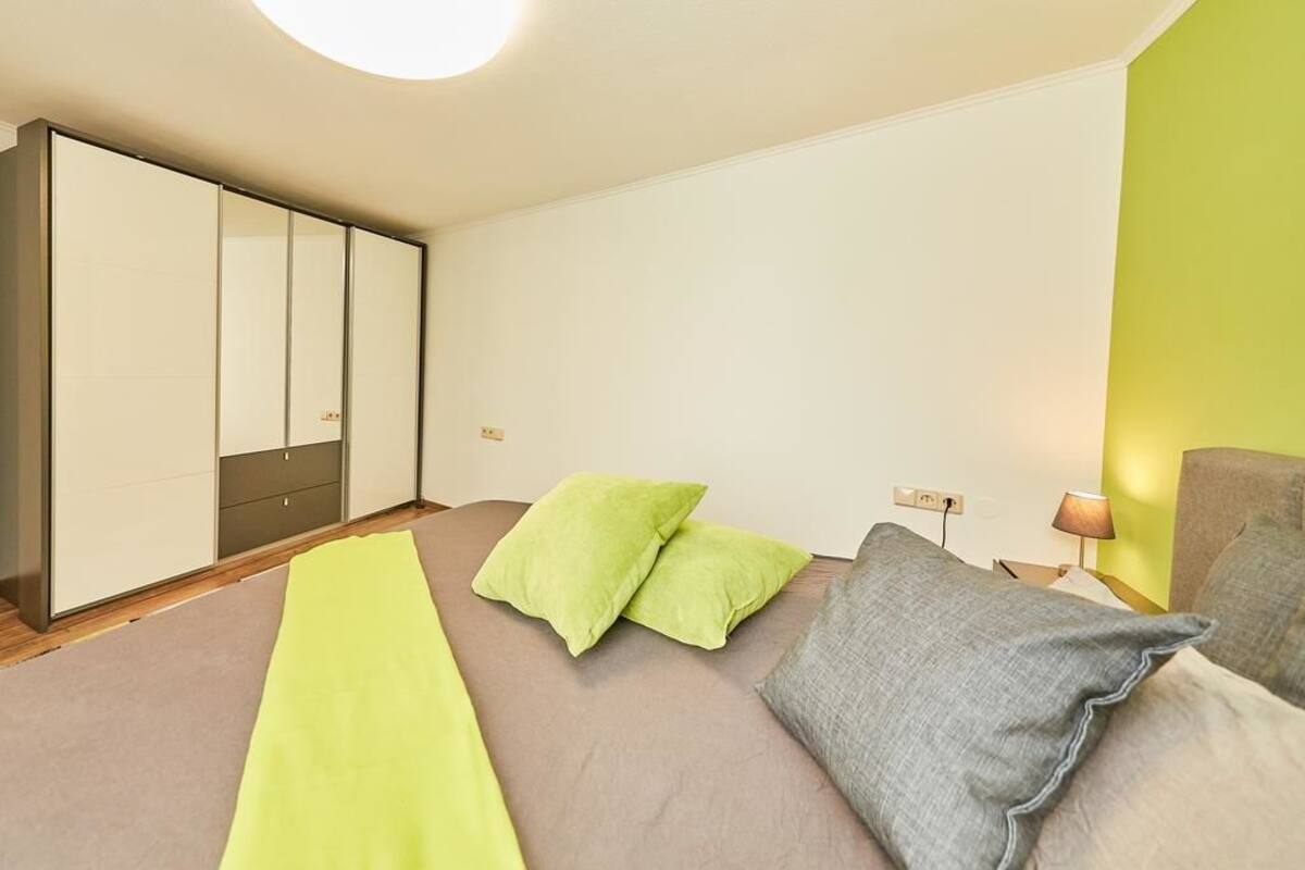 A bedroom with a bed, pillows, a nightstand, and a wardrobe.