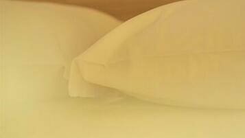 Primer plano de una cama con ropa de cama blanca.