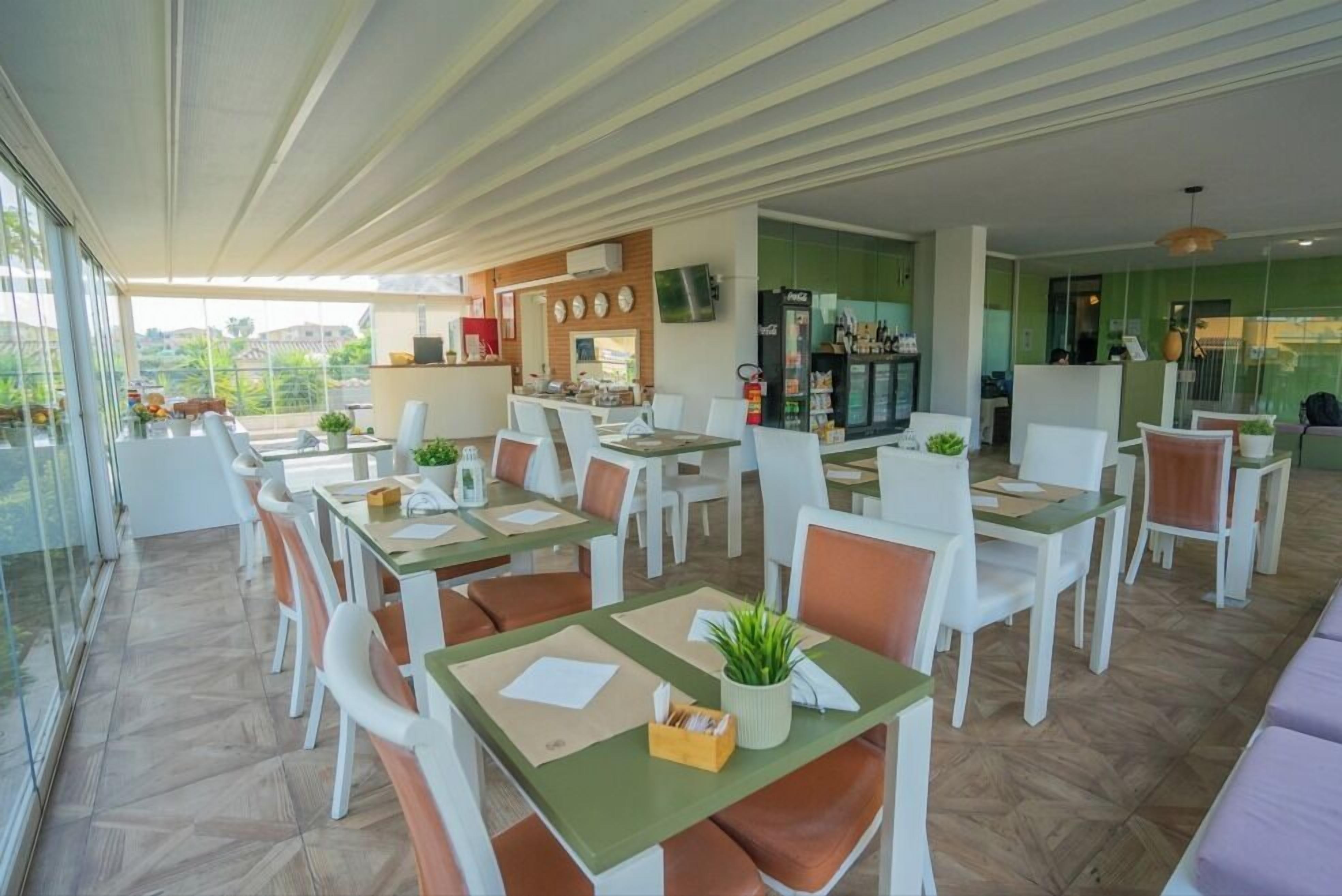 A modern restaurant with glass walls, white and brown chairs, and a green table.