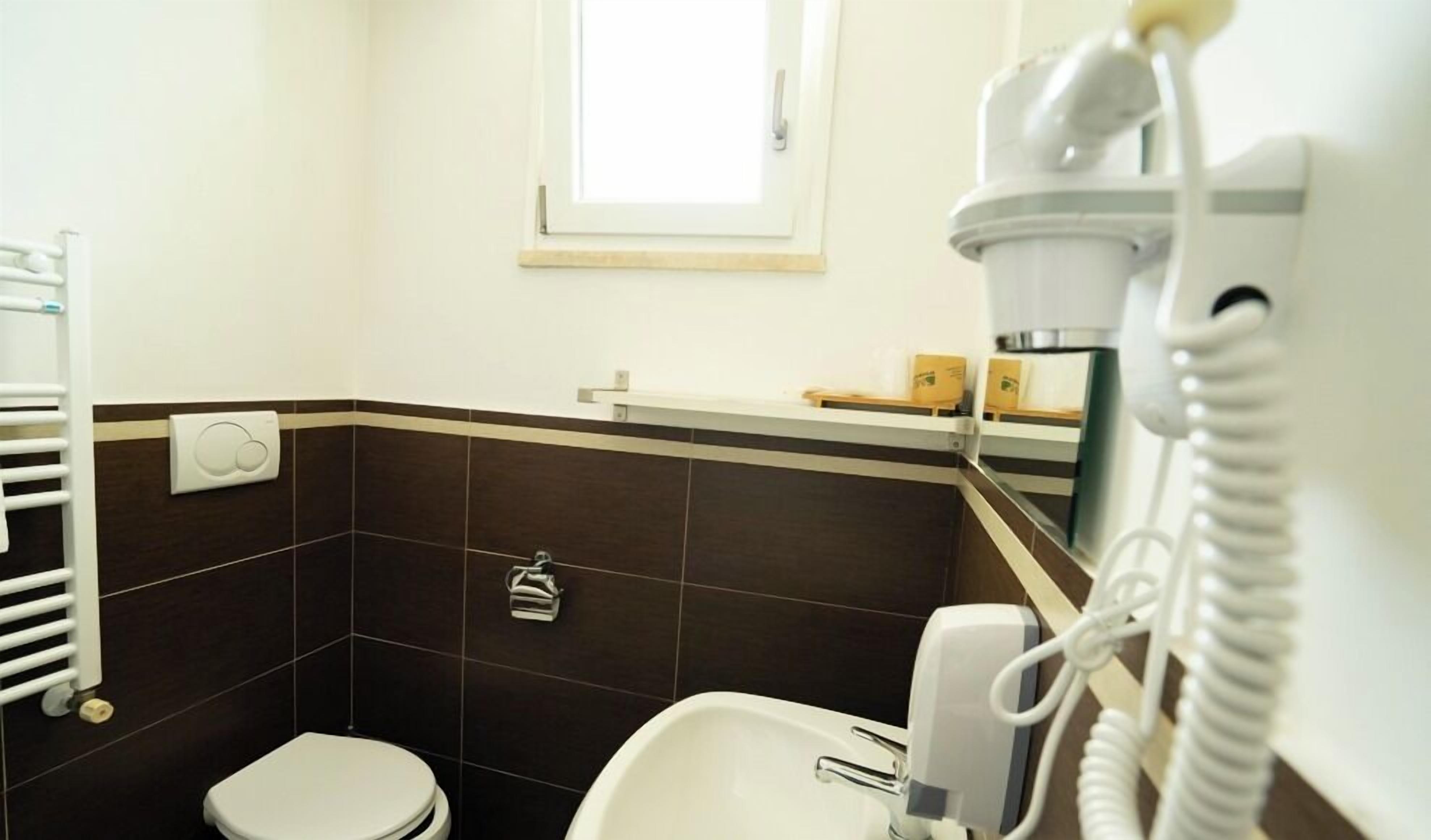 A bathroom with a toilet, a bidet, a towel rack, and a hand dryer.