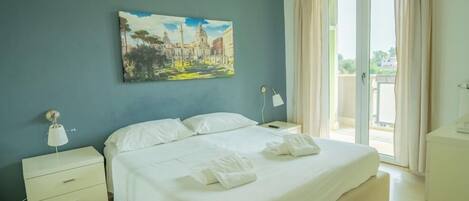A hotel room with a bed, a nightstand, a painting on the wall, and a view of the outside.