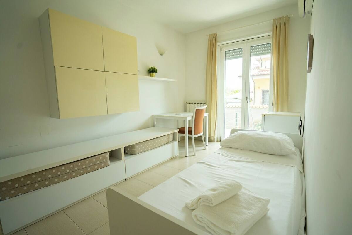 A bedroom with a bed, a desk, a chair, and a wardrobe.