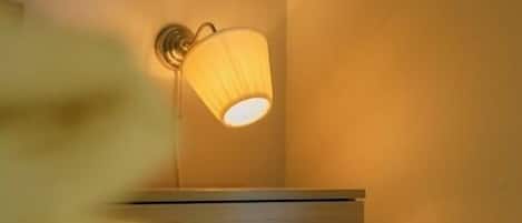 A wall-mounted lamp with a cylindrical shade against a plain wall.