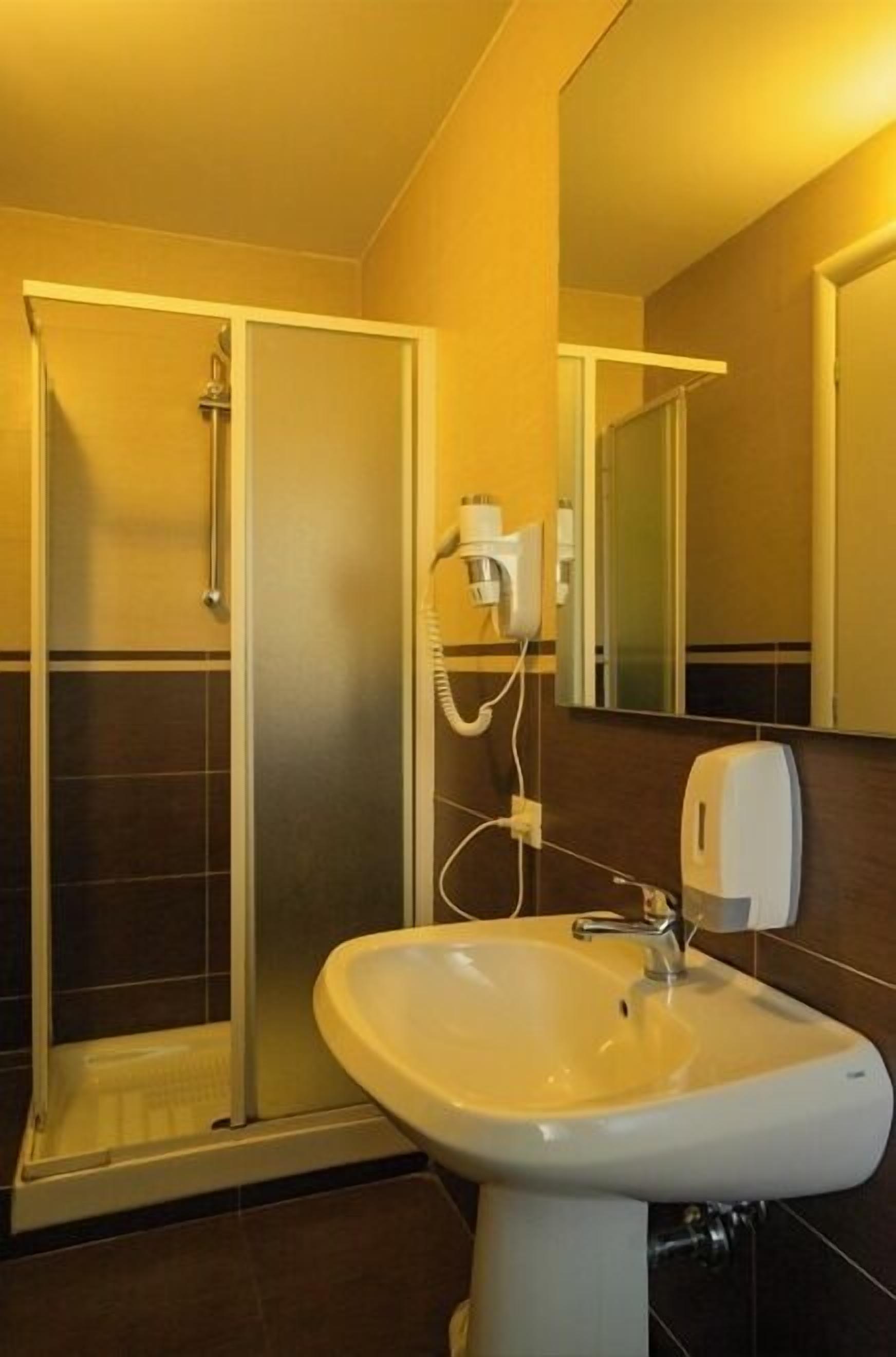 Un baño con ducha, lavamanos y espejo.