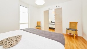 A modern bedroom with a large bed, a mirror, and two wicker chairs. - Auszeit (Bernkastel-Kues)