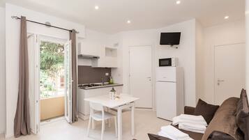Una cocina moderna con armarios blancos, una mesa de comedor y un televisor de pantalla plana montado arriba.