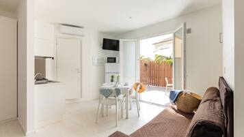 A compact living space with a kitchenette, a dining area, and a sofa.