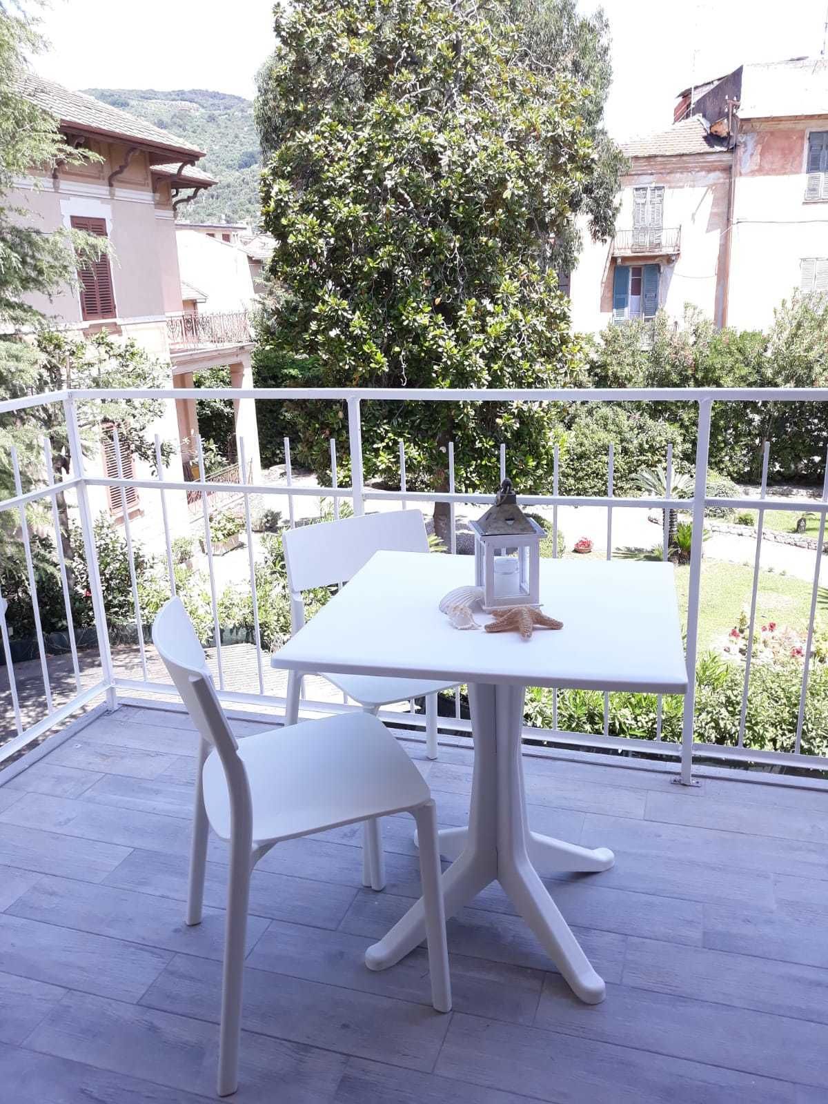 Un balcone in metallo bianco con un tavolo e sedie, circondato da una ringhiera bianca.