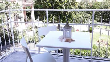 Un balcone in metallo bianco con un tavolo e sedie, circondato da una ringhiera bianca.