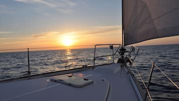 A boat's deck with a view of the sunset over the ocean.
