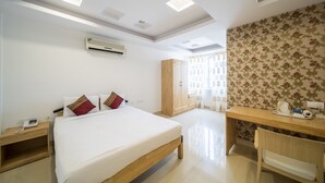Une chambre d’hôtel équipée d’un lit, d’une table de chevet, d’un bureau, d’une chaise, d’une armoire et d’un appareil de climatisation.