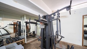 Une salle de sport équipée de matériel d’exercice, d’un banc et d’haltères.