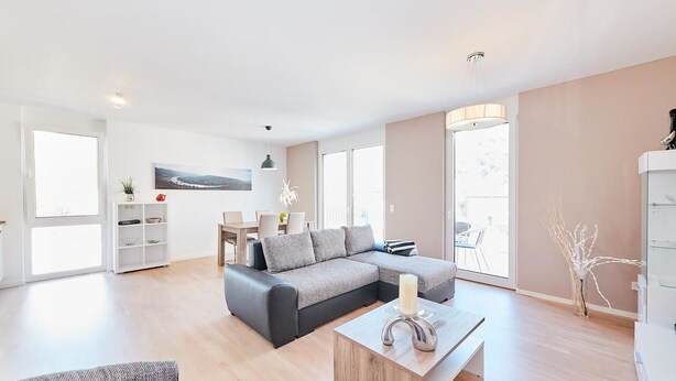 Een moderne woonkamer met een modulaire bank, een salontafel en een eethoek met een tafel en stoelen.