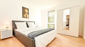 Een slaapkamer met een bed, nachtkastjes, een kledingkast en een raam.
