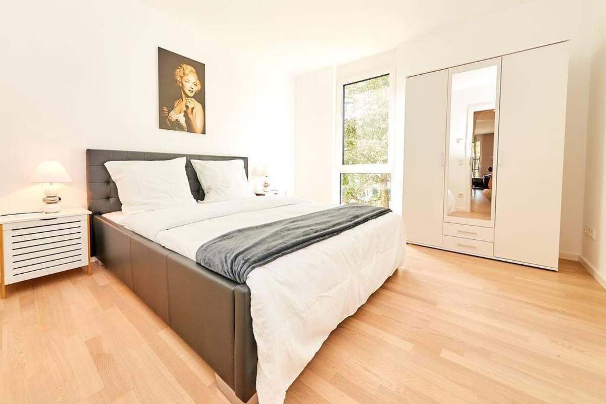 Un dormitorio con cama, mesitas de noche, armario y ventana.