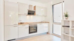 Een moderne keuken met witte kasten, een inbouwoven en een raam voor natuurlijk licht.