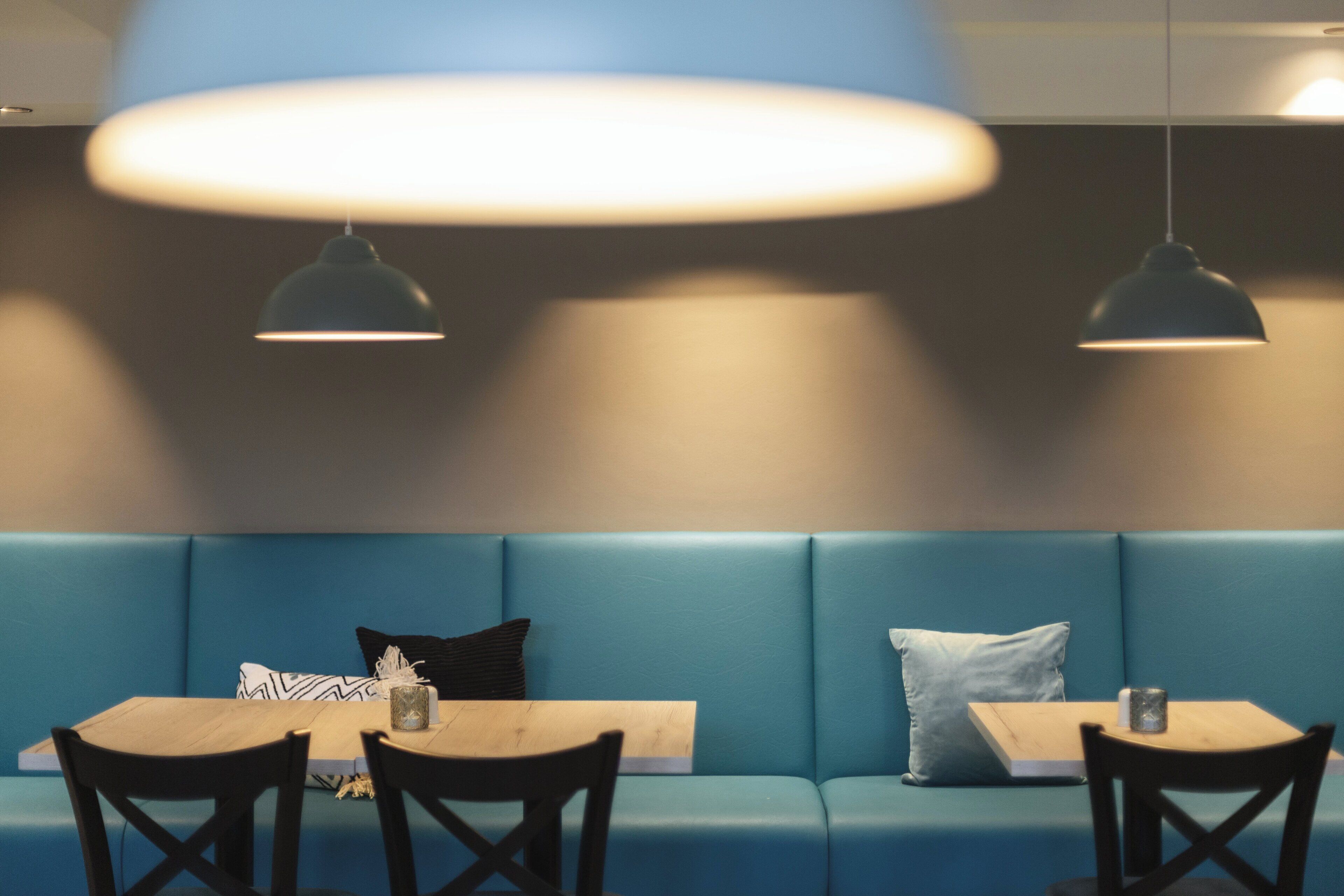 Ein moderner Sitzbereich mit einer blauen gepolsterten Bank, einem Holztisch und zwei schwarzen Stühlen.