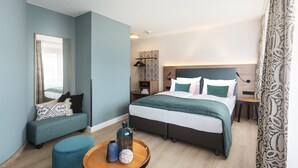 A modern hotel room with a large bed, a seating area, and a small table with decorative items.
