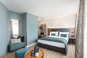 Ein modernes Hotelzimmer mit einem großen Bett, einer Sitzecke und einem kleinen Tisch mit Dekorationen.