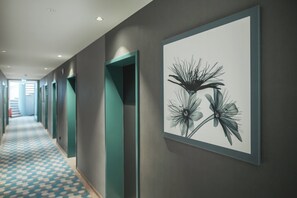 A hallway with teal-colored doors and a framed botanical artwork on the wall.