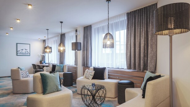 A modern hotel lobby with sofas, a coffee table, and pendant lighting.