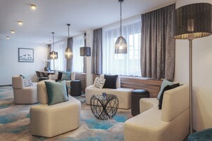 Eine moderne Hotelhalle mit Sofas, einem Couchtisch und Pendelleuchten.