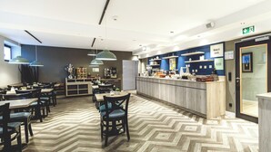 A modern restaurant with a herringbone floor pattern, pendant lighting, and a counter with a 'Make it yours' sign.